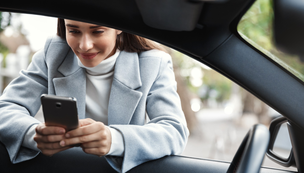 empresaria apoyado ventanilla coche mensaje texto telefono sonriendo feliz